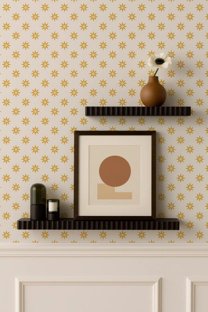 a wall with a patterned wallpaper, two black shelves mounted on the wall, and a framed picture and a vase on the top shelf.
