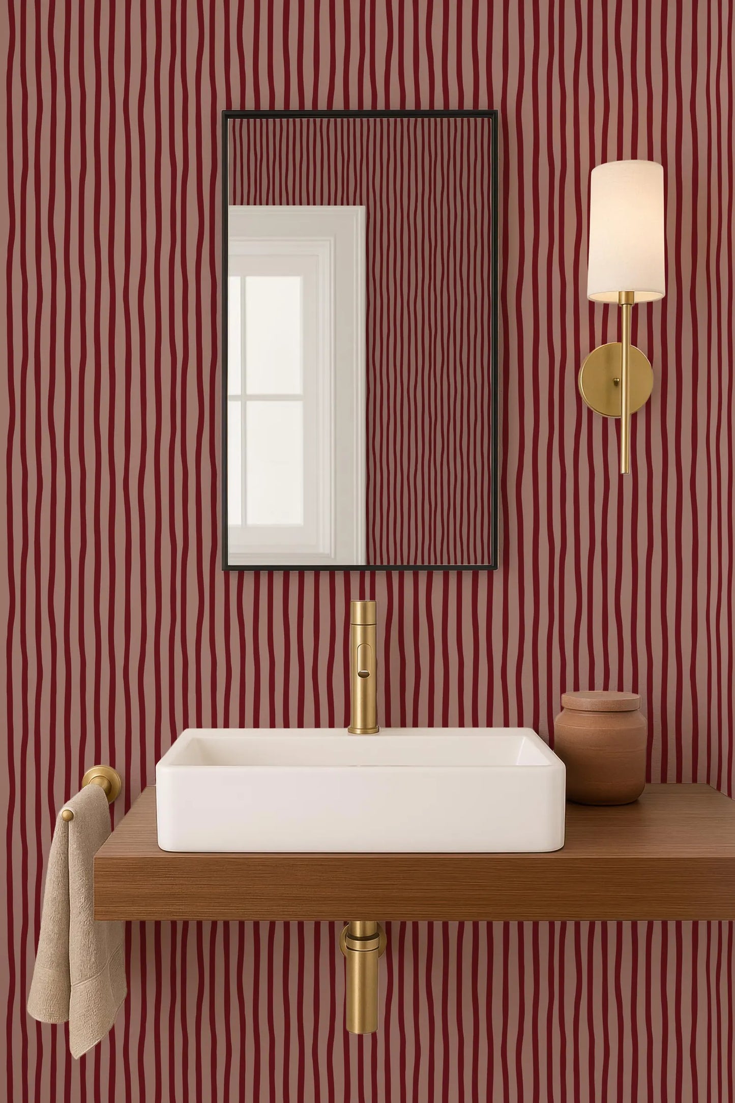 a bathroom with a white rectangular sink, a mirror above it, and a wooden shelf below the sink. The walls are covered in a red and black striped wallpaper, and there is a gold-colored light fixture mounted on the wall.