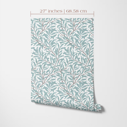 a patterned wallpaper or wall covering with a repeating design of green leaves and branches. The pattern is displayed on a white background, and there is a measurement scale indicating the size of the pattern in inches and centimeters.