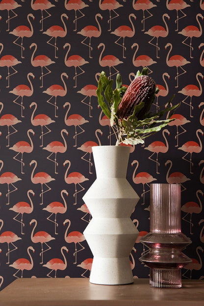 a white vase with a bouquet of flowers and a pink vase with a purple flower on a dark background with a repeating pattern of pink flamingos.