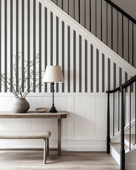 a modern and minimalist interior design with a black and white striped wall, a wooden table with a lamp, a bench, and a staircase.