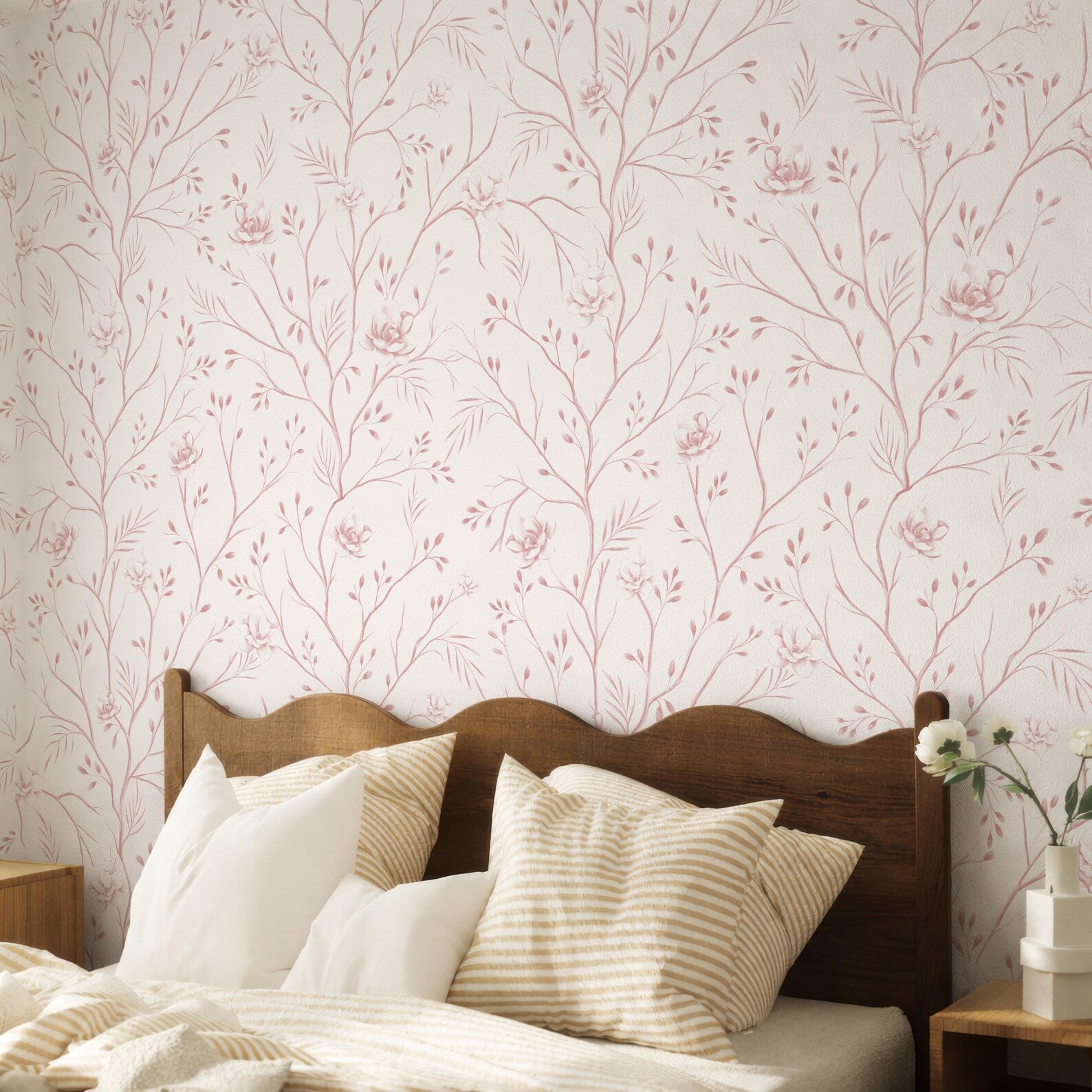 a bedroom with a wooden headboard and a bed covered in white and beige striped pillows. The wall behind the bed has a floral wallpaper pattern in shades of pink and white.