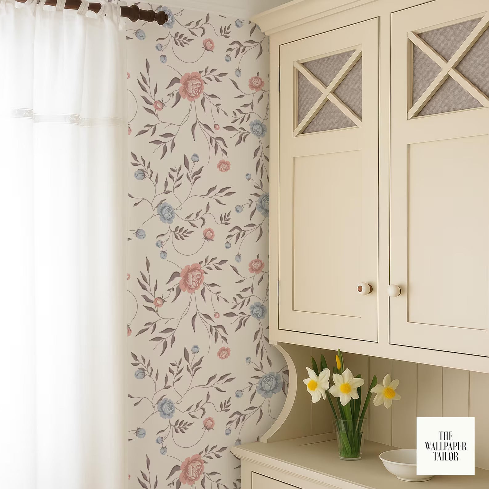 a white cabinet with a floral pattern on the wall behind it, and a vase of white flowers on a shelf below the cabinet.