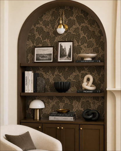 a cozy living room with a bookshelf filled with various decorative items, including books, a lamp, and a sculpture. The bookshelf is set against a wall with a floral wallpaper, creating a warm and inviting atmosphere.
