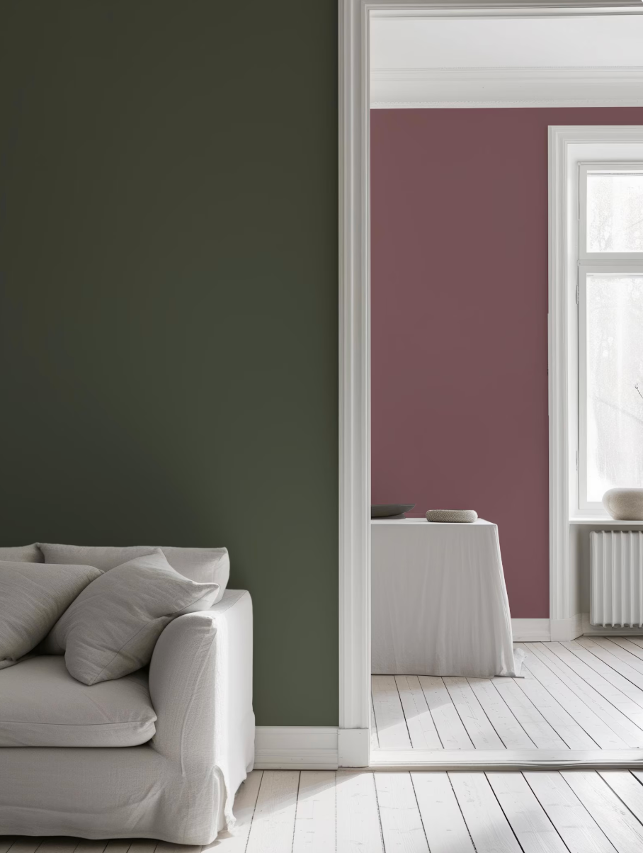 a modern living room with a white sofa and a white table covered with a white tablecloth. The room has a green accent wall and a white floor, creating a clean and minimalist aesthetic.