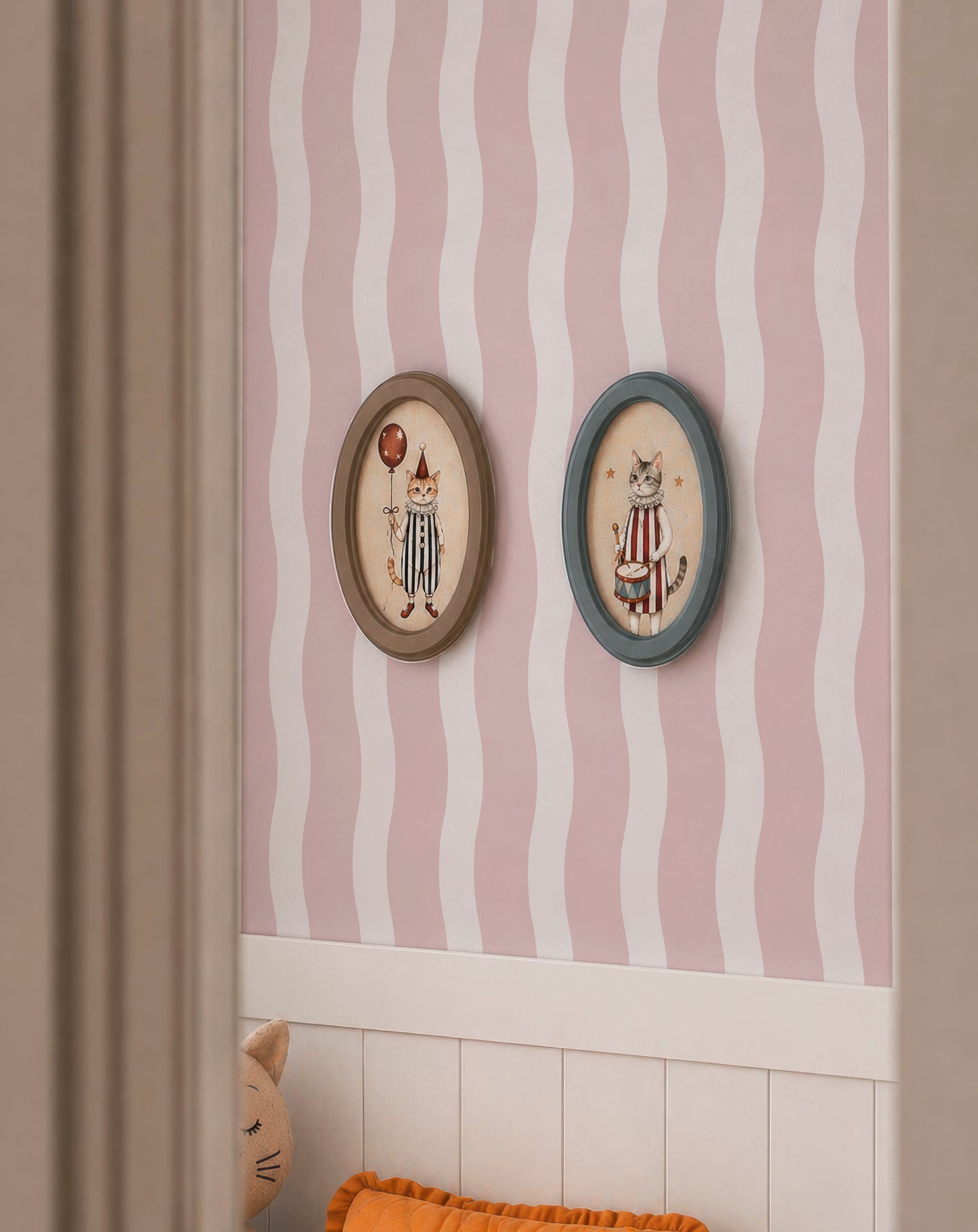 two framed pictures of cats, each with a unique design and color scheme, hanging on a wall with a pink and white striped pattern.