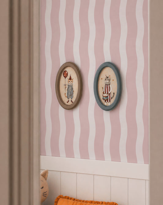 two framed pictures of cats, each with a unique design and color scheme, hanging on a wall with a pink and white striped pattern.