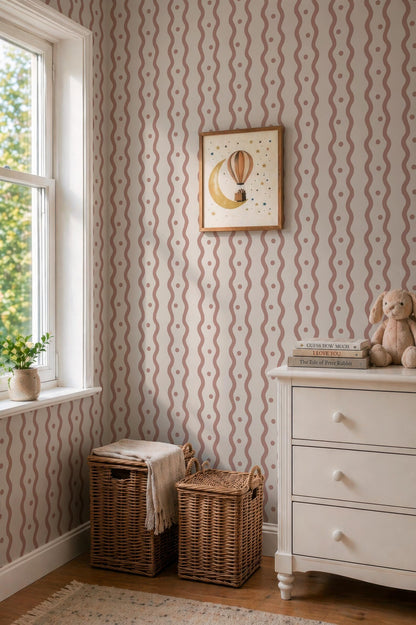 a cozy corner of a room with a dresser, a window, and a picture frame. The dresser has a white surface and two wicker baskets on the floor. The window is adorned with a white curtain, and a picture frame hangs on the wall above the dresser. The walls are decorated with a striped pattern, and a small stuffed animal is placed on the dresser.