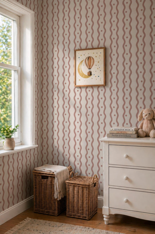 a cozy corner of a room with a dresser, a window, and a picture frame. The dresser has a white surface and two wicker baskets on the floor. The window is adorned with a white curtain, and a picture frame hangs on the wall above the dresser. The walls are decorated with a striped pattern, and a small stuffed animal is placed on the dresser.