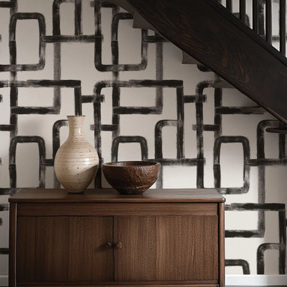 a wooden cabinet with two decorative items on top, including a white vase and a brown bowl, set against a black and white geometric patterned wall.