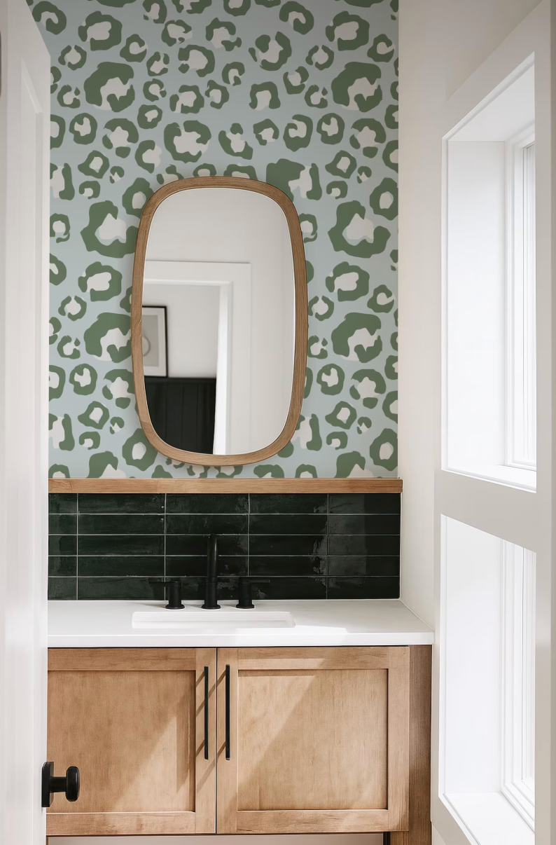 a bathroom with a white sink, a mirror above it, and a leopard print wallpaper on the wall.