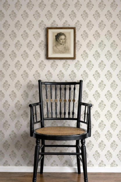a black wooden chair with a woven seat, positioned against a wall with a floral wallpaper. Above the chair, there is a framed portrait of a woman.