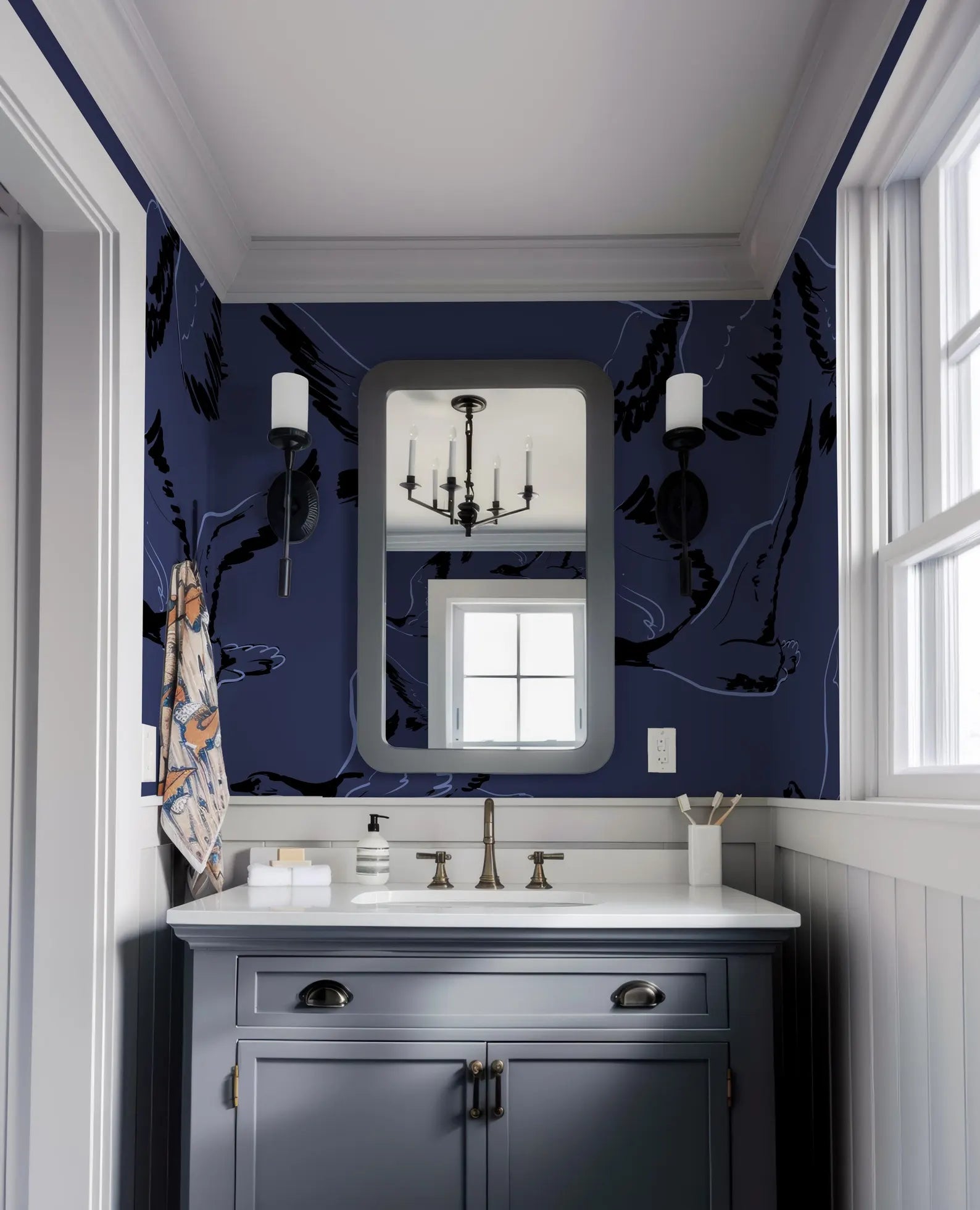 a bathroom with a white sink and a mirror above it. The walls are painted in a dark blue color, and there are two light fixtures on either side of the mirror. The overall design and decor of the bathroom appear to be modern and stylish.