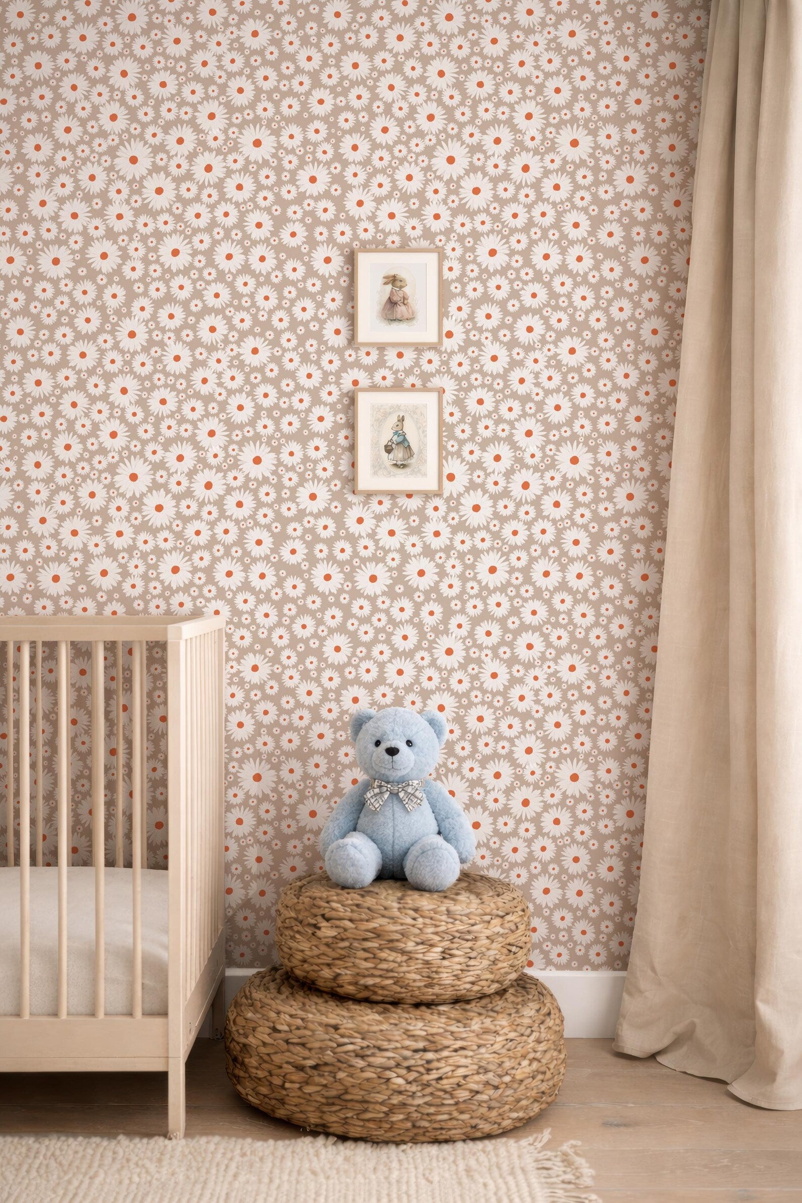 A cozy nursery scene with a wooden crib, a blue teddy bear, and a woven basket on the floor. The walls are covered in a floral wallpaper, and there are two framed pictures hanging above the crib.