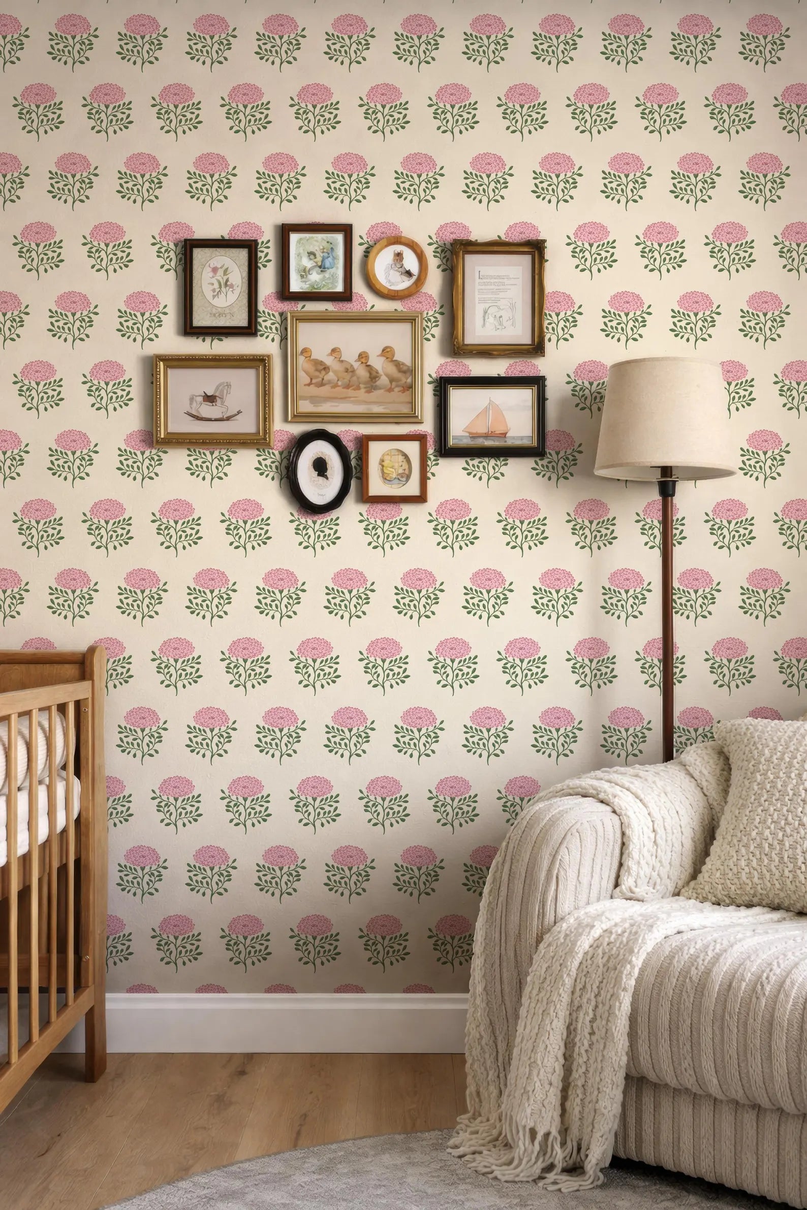 a cozy living room with a white sofa, a wooden rocking chair, and a lamp. The walls are decorated with a floral wallpaper pattern, and there are several framed pictures and photographs arranged on the wall.