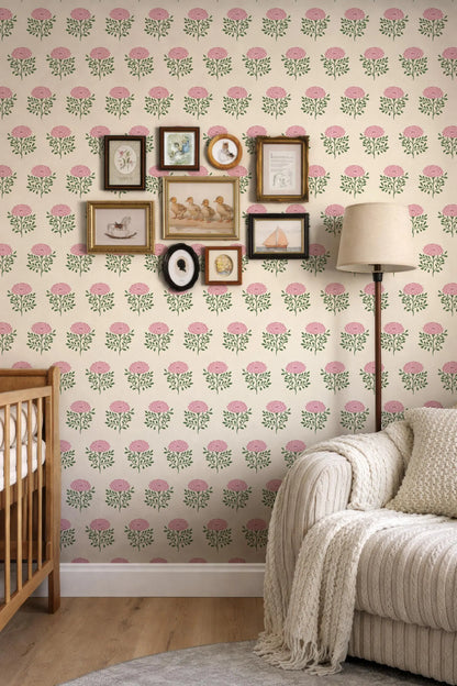 a cozy living room with a white sofa, a wooden rocking chair, and a lamp. The walls are decorated with a floral wallpaper pattern, and there are several framed pictures and photographs arranged on the wall.