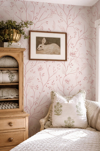 a cozy bedroom with a floral wallpaper, a wooden dresser, and a framed picture of a rabbit on the wall.