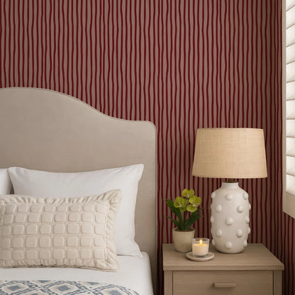 a cozy bedroom scene with a bed, a nightstand, and a lamp. The bed has a beige headboard and white pillows, and the nightstand has a white lamp with a beige shade. There is also a small potted plant on the nightstand.