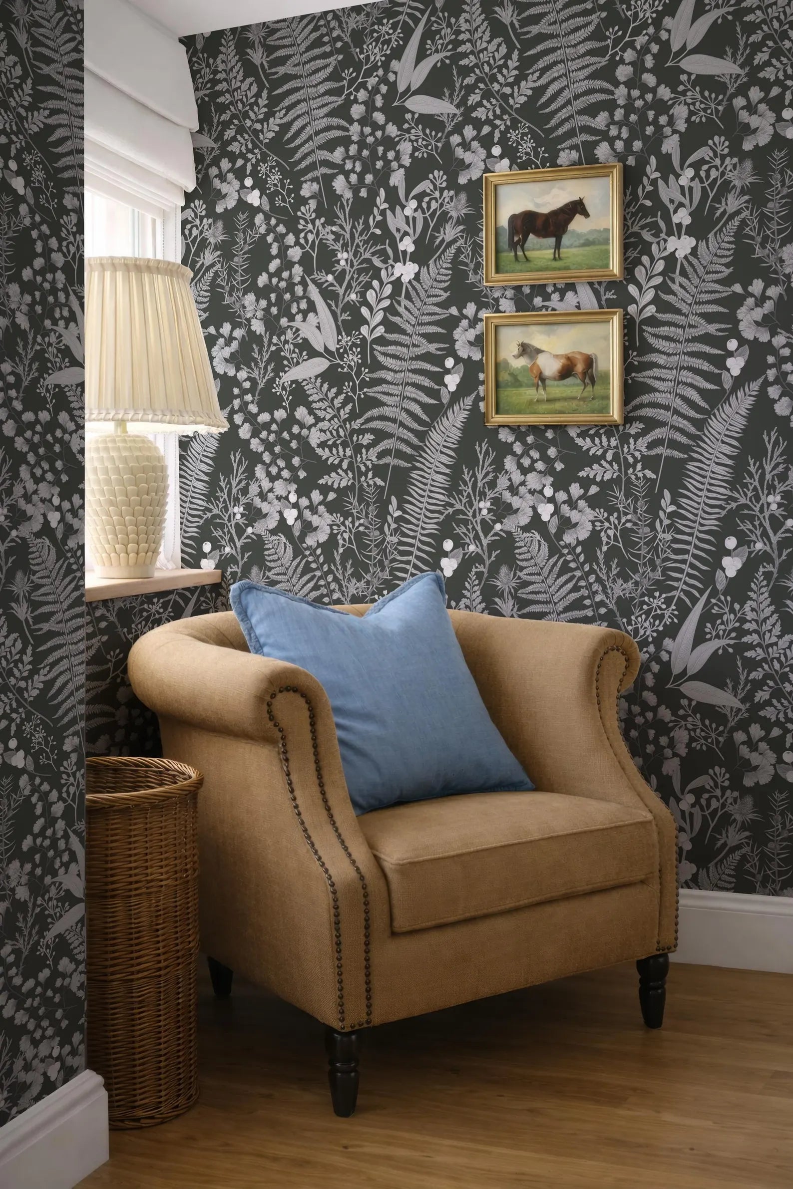 a cozy corner of a room with a beige armchair, a wicker basket, and a framed picture of a horse on the wall.