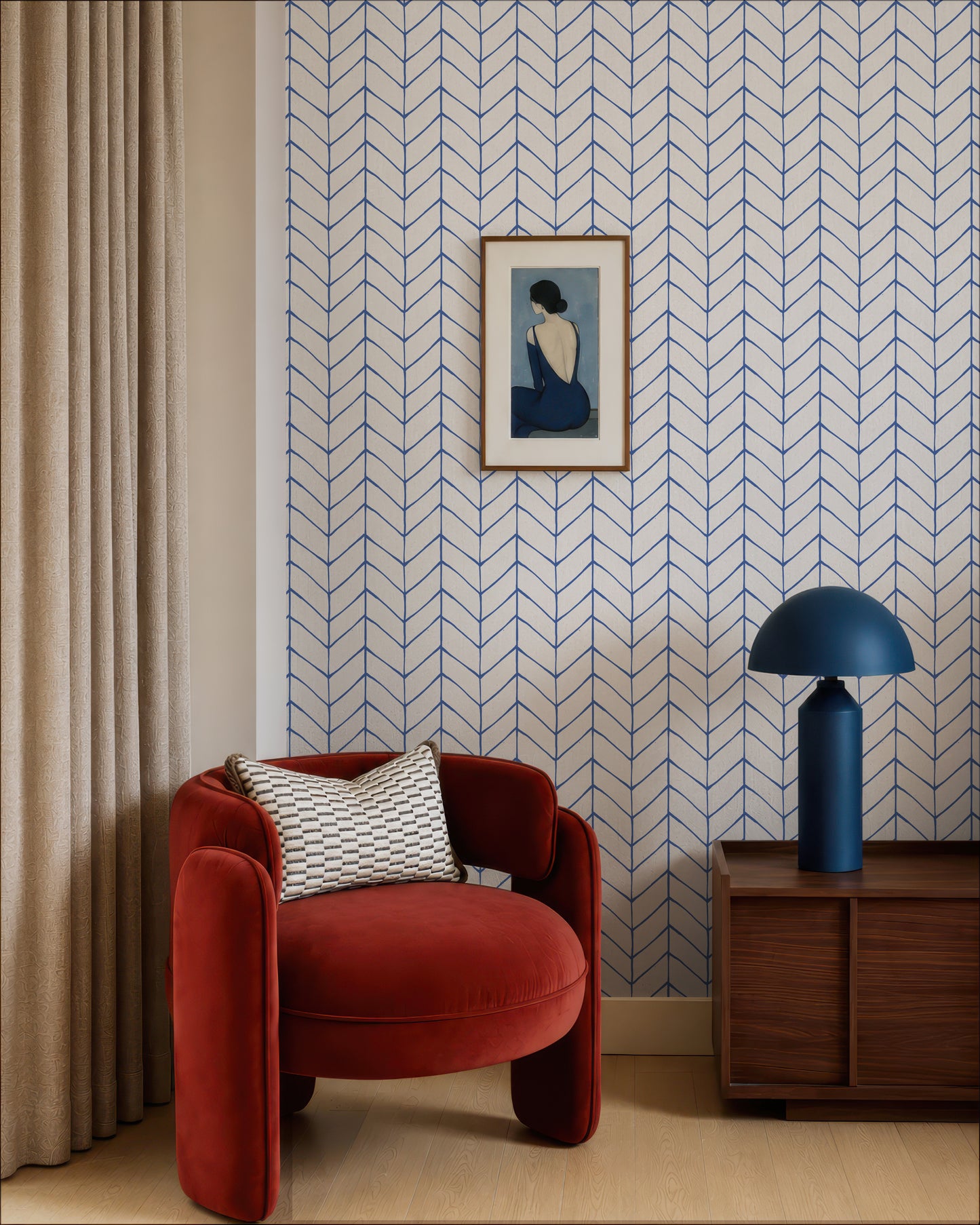 a modern living room with a red armchair, a wooden side table with a blue lamp, and a framed artwork on the wall.
