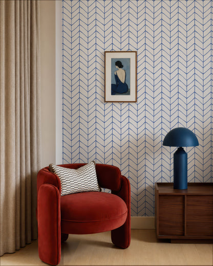 a modern living room with a red armchair, a wooden side table with a blue lamp, and a framed artwork on the wall.