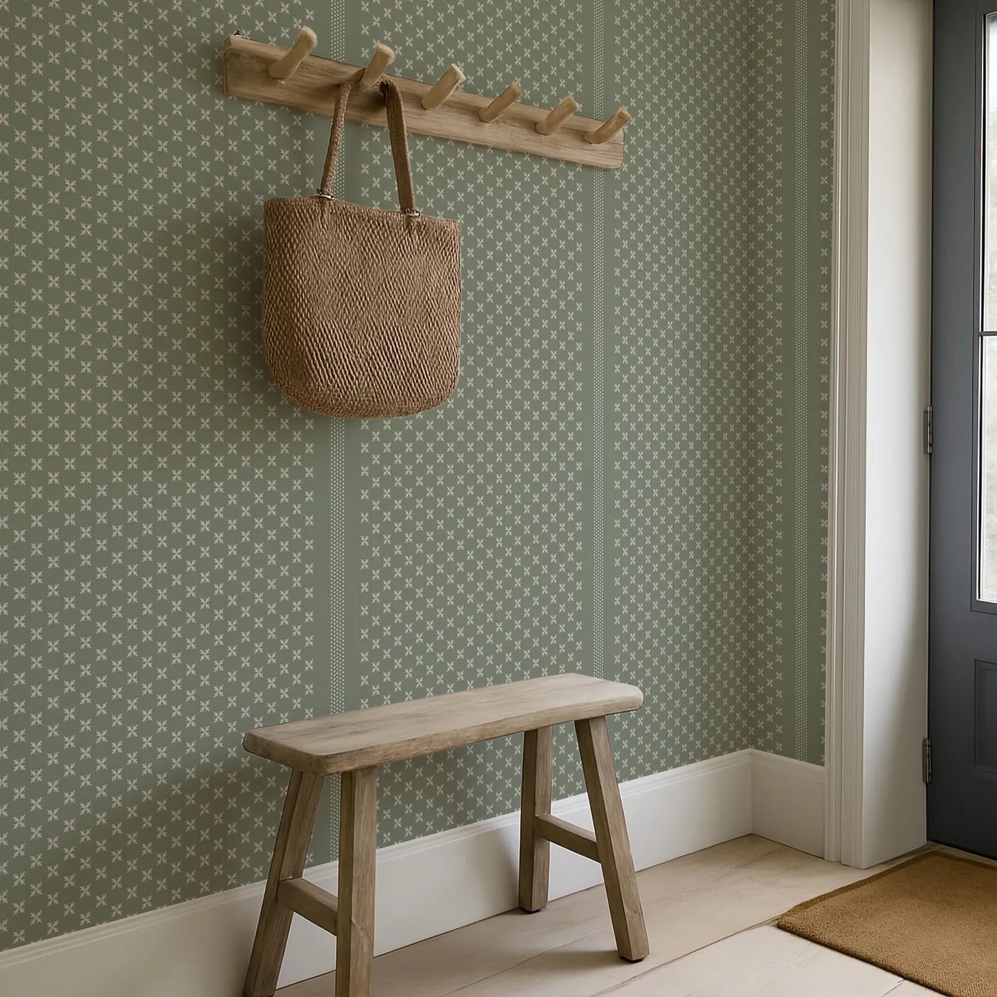 a wooden bench with a woven bag hanging on a wooden coat rack above it, set against a green and white patterned wall.