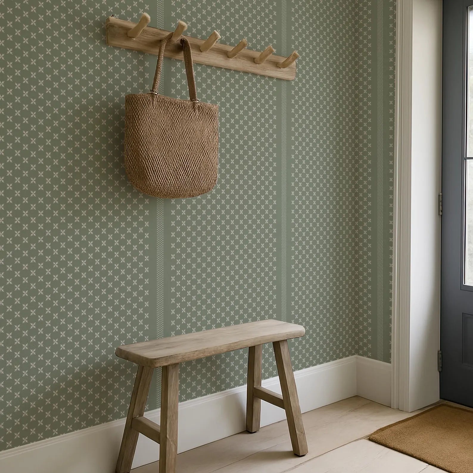 a wooden bench with a woven bag hanging on a wooden coat rack above it, set against a green and white patterned wall.