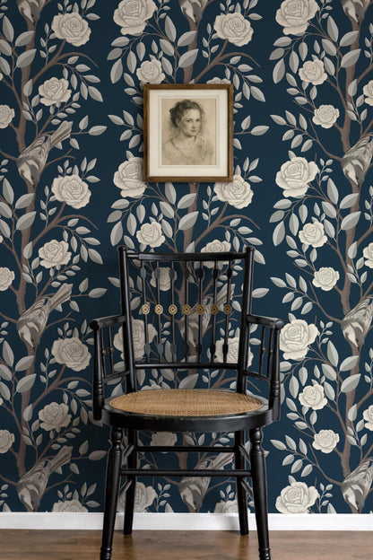 a black wooden chair with a woven seat, positioned in front of a wall with a floral wallpaper pattern. Above the chair, there is a framed portrait of a woman.