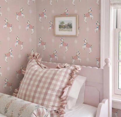 a pink and white checkered pillow on a bed, with a framed picture of a horse on the wall above it.