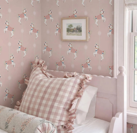 a pink and white checkered pillow on a bed, with a framed picture of a horse on the wall above it.