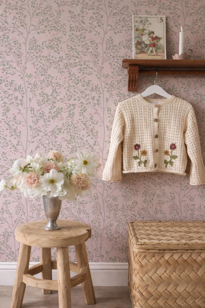 a cozy and charming interior with a wooden stool, a vase of flowers, and a wooden shelf displaying a sweater with floral embroidery.
