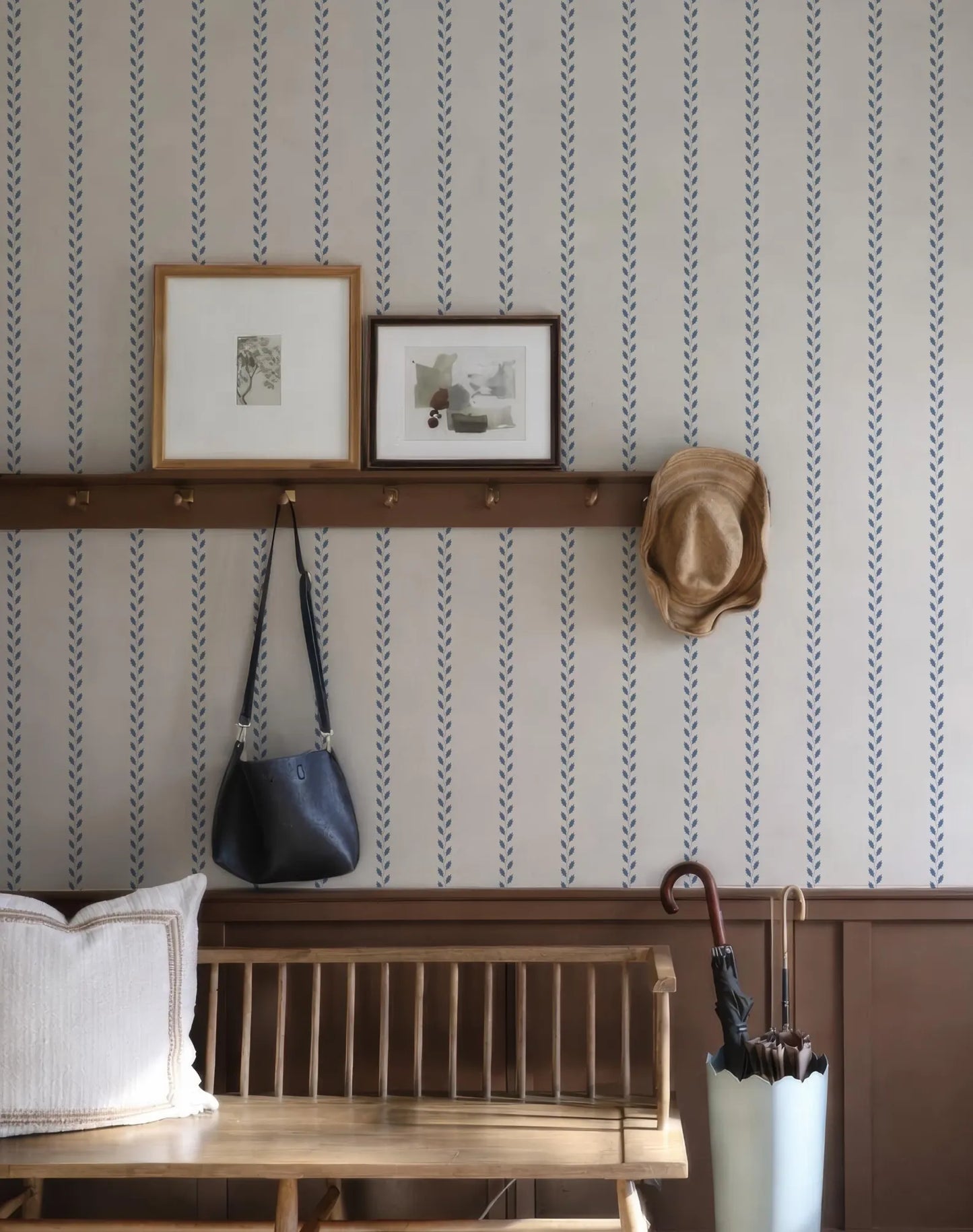 a cozy entryway with a wooden bench, a shelf displaying framed pictures, a hat rack, and a white umbrella.