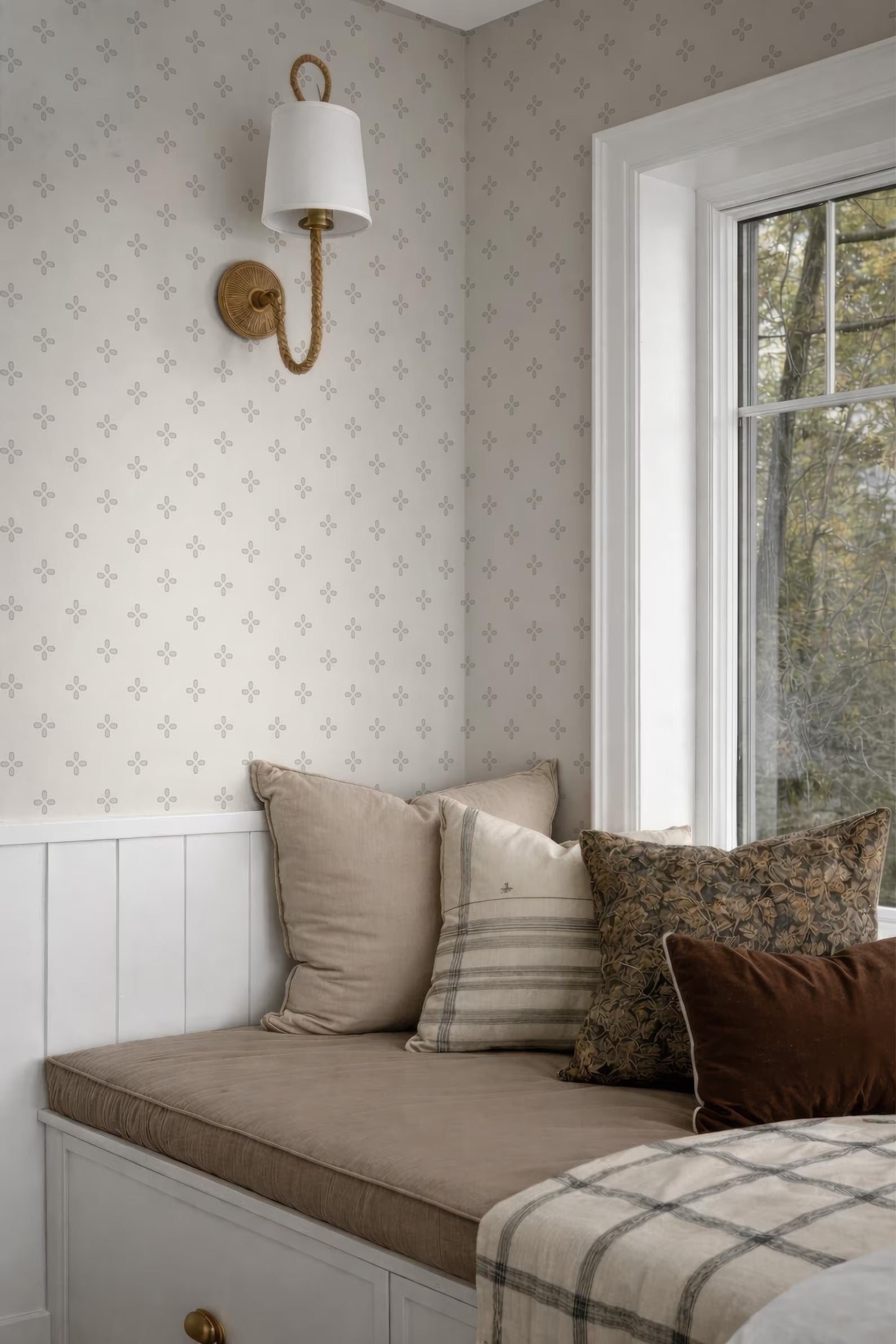 a cozy bedroom with a white wall, a window, and a bed with a brown and white striped pillow.