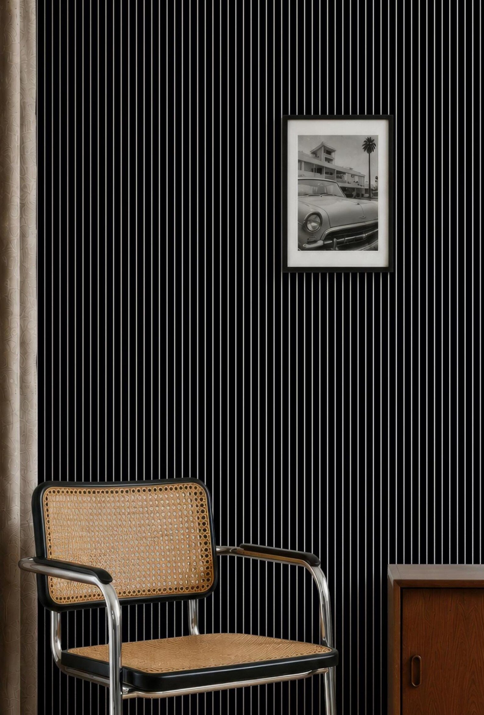 a black and white photograph of a car on a wall, with a woven chair placed in front of it.