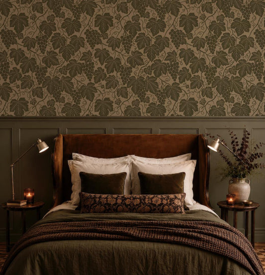a cozy bedroom with a large bed, a brown headboard, and a patterned wallpaper. The bed is adorned with white and brown pillows, and there are two nightstands on either side of the bed with lamps. The room has a warm and inviting atmosphere, with a vase of flowers and a candle on one of the nightstands.
