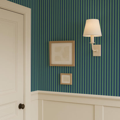 a wall with a striped green and blue pattern, and there are three framed artworks hanging on the wall.
