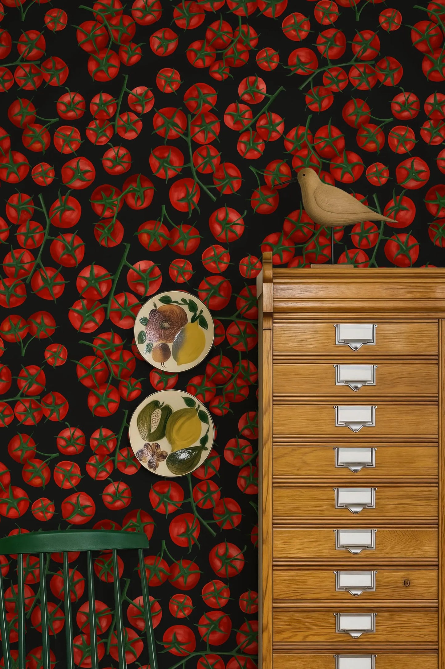 a vibrant and colorful wallpapered wall with a wooden cabinet and a bird perched on top. The wall is adorned with a pattern of red tomatoes, and there are two plates with fruit designs placed on the wall.