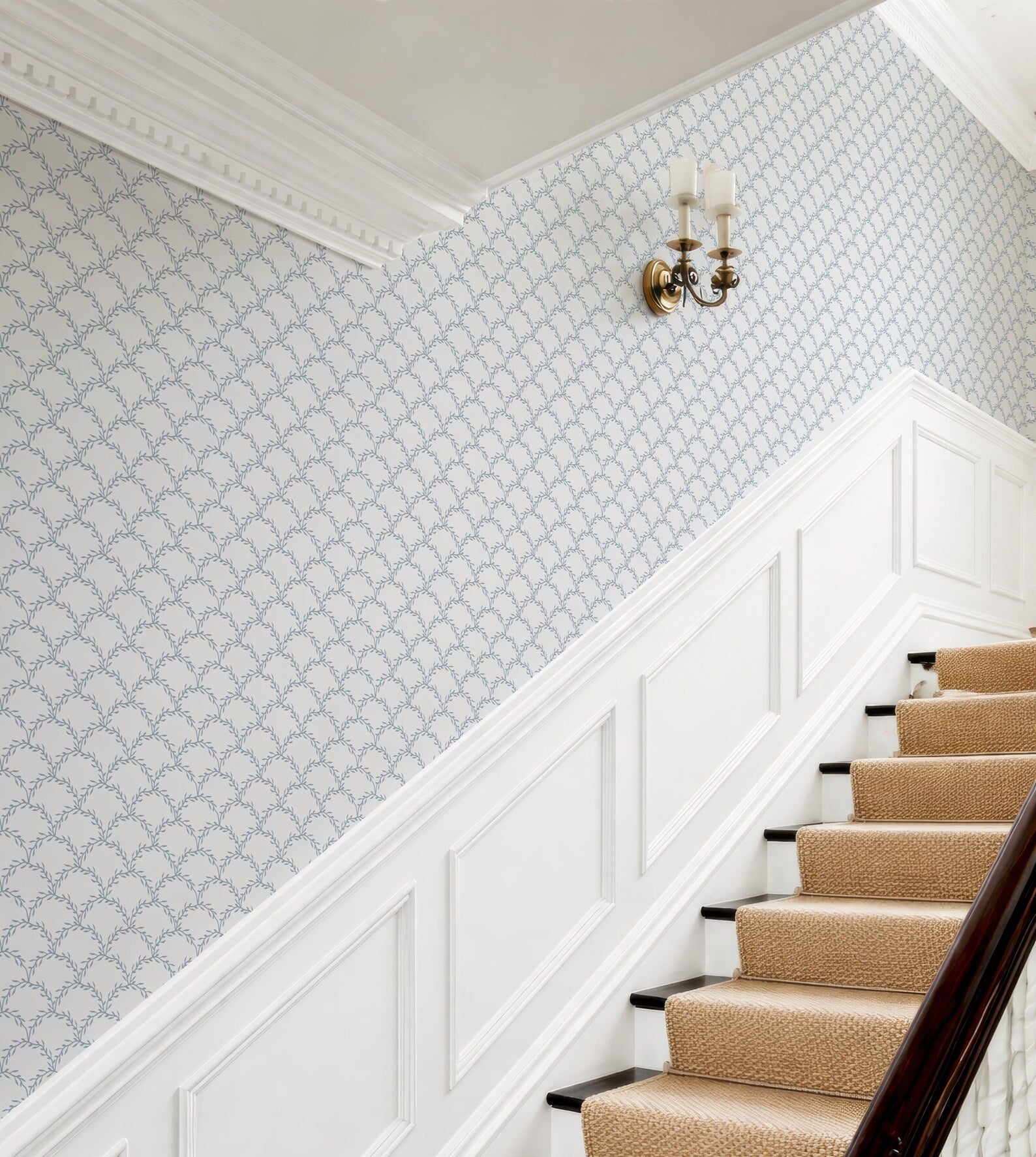 a staircase with a patterned wallpaper on the walls and a wall-mounted light fixture above the stairs.