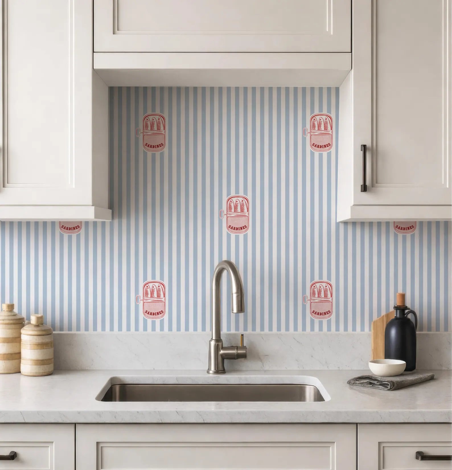 a kitchen with a white sink and cabinets, and a backsplash with blue and white striped patterns. There are also some decorative items on the counter, such as a bottle and a bowl.