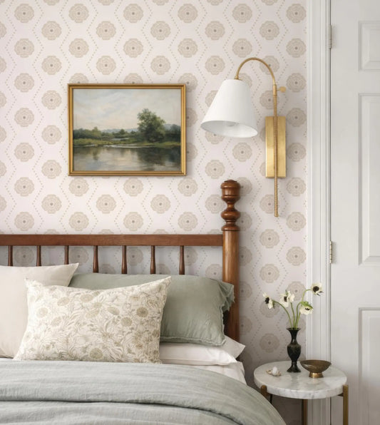 a cozy bedroom with a wooden headboard, a framed landscape painting on the wall, and a lamp with a white shade on a side table.