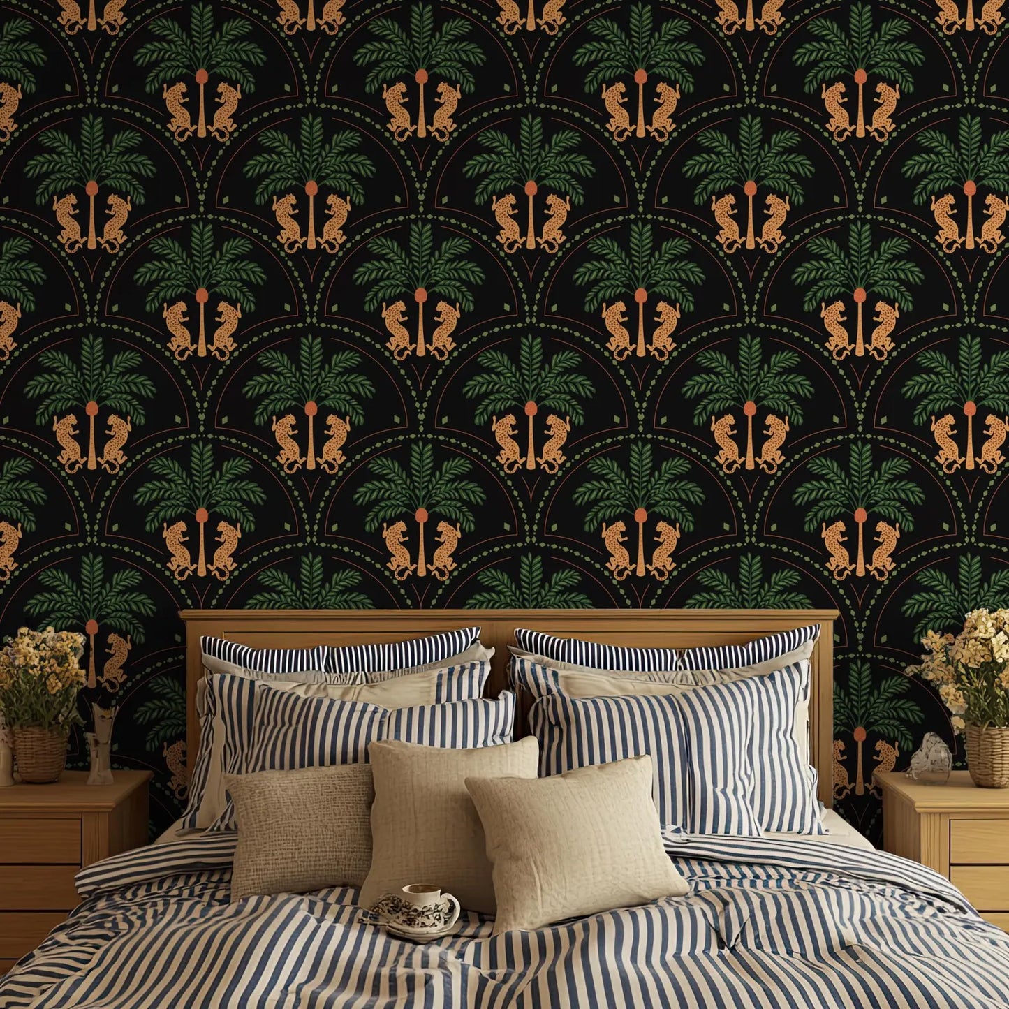 a bedroom with a large bed adorned with striped bedding and pillows. The bed is set against a wall with a repeating pattern of palm trees and lions, creating a tropical ambiance. The room also includes a nightstand on each side of the bed, and a vase of flowers on one of the nightstands.