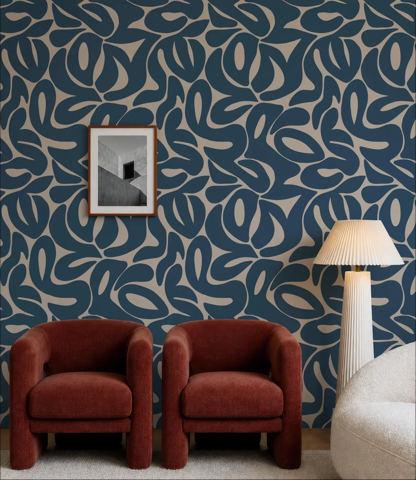 a living room with a blue and white patterned wallpaper, two red armchairs, and a white floor lamp.