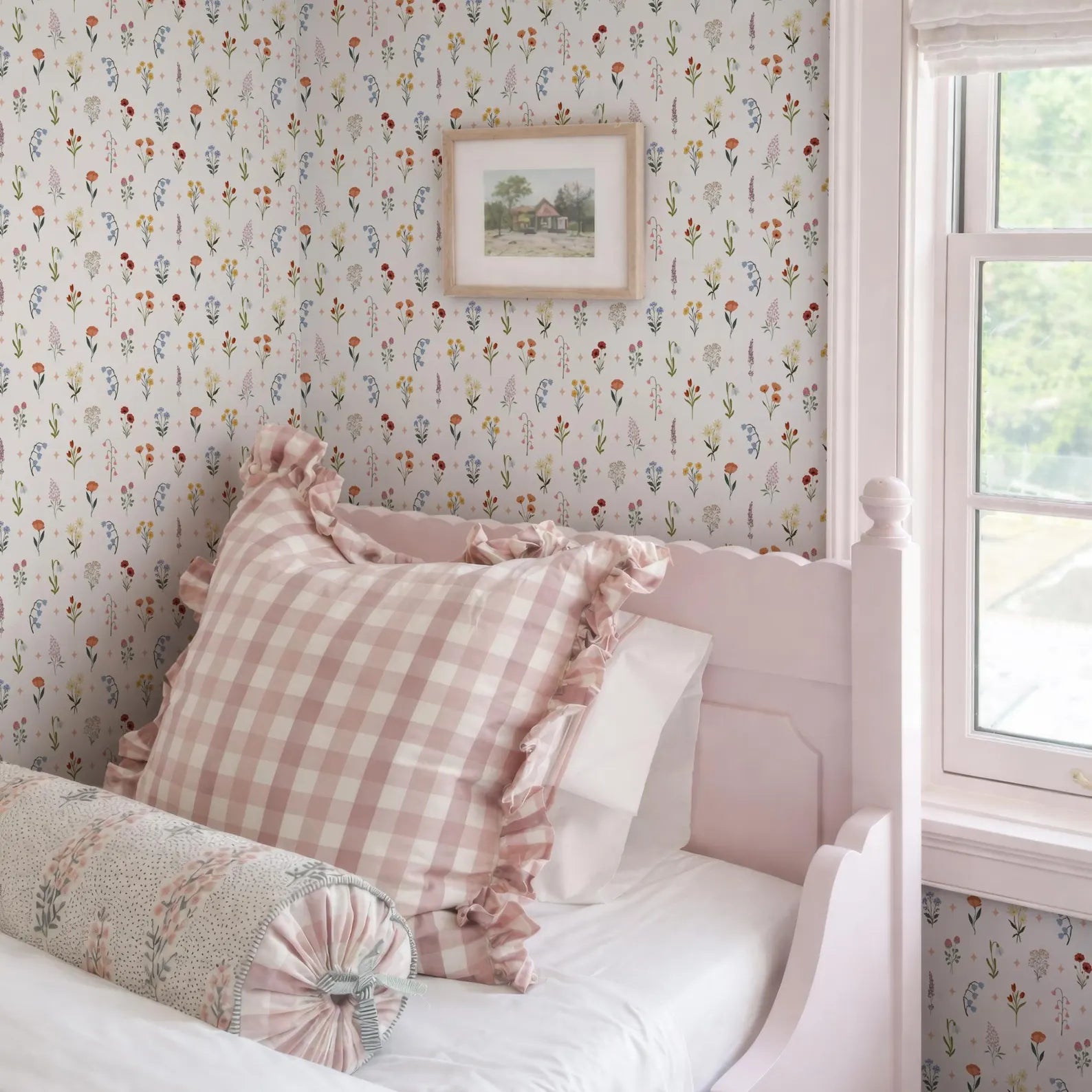 a cozy bedroom with a pink bed frame, a checkered pillow, and a framed picture on the wall.