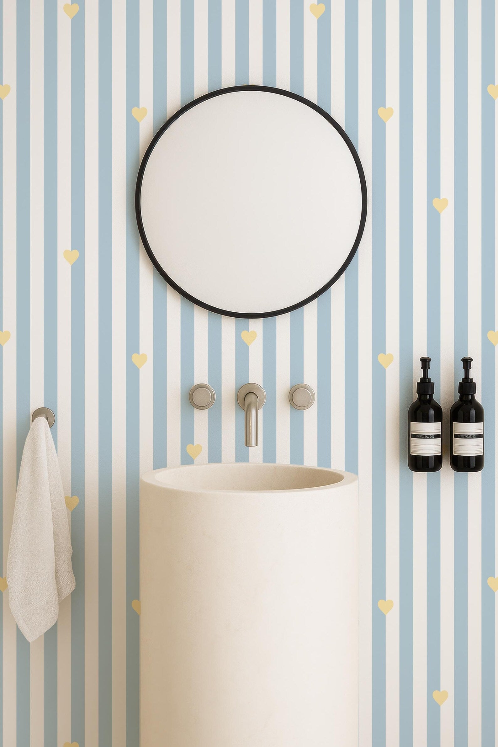 a bathroom with a white sink, a round mirror, and a blue and white striped wall with small yellow hearts.