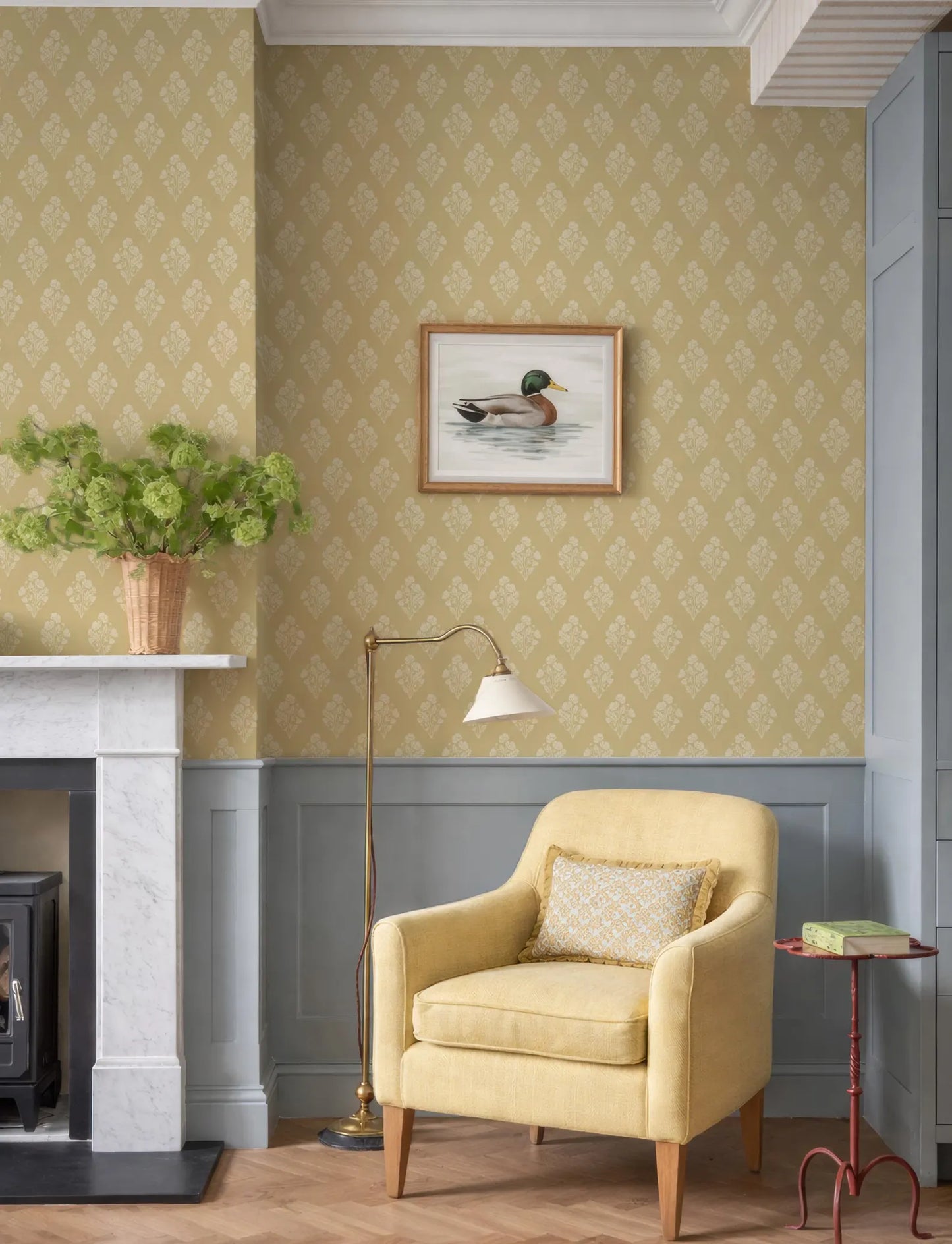 a cozy living room with a yellow armchair, a fireplace, a framed picture of a duck, and a floor lamp.