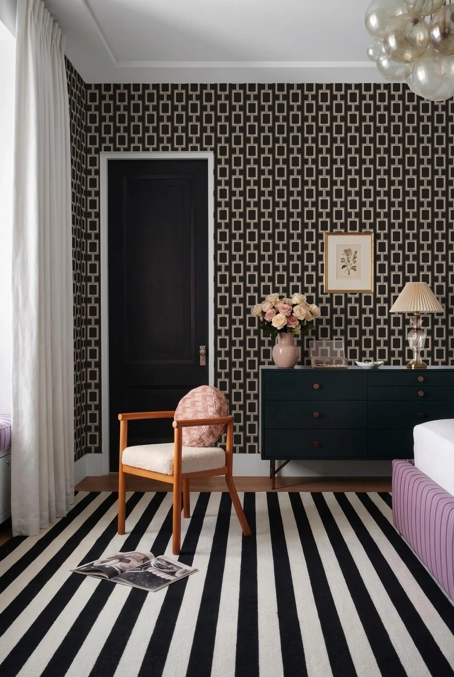 a bedroom with a black and white striped rug, a black dresser, a wooden chair, and a framed picture on the wall.