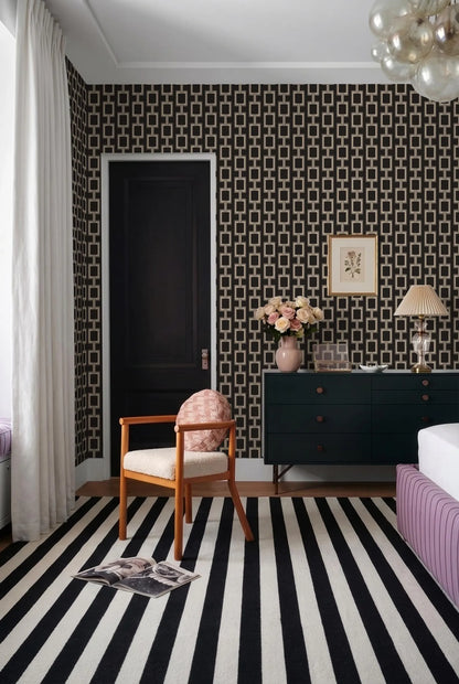 a bedroom with a black and white striped rug, a black dresser, a wooden chair, and a framed picture on the wall.