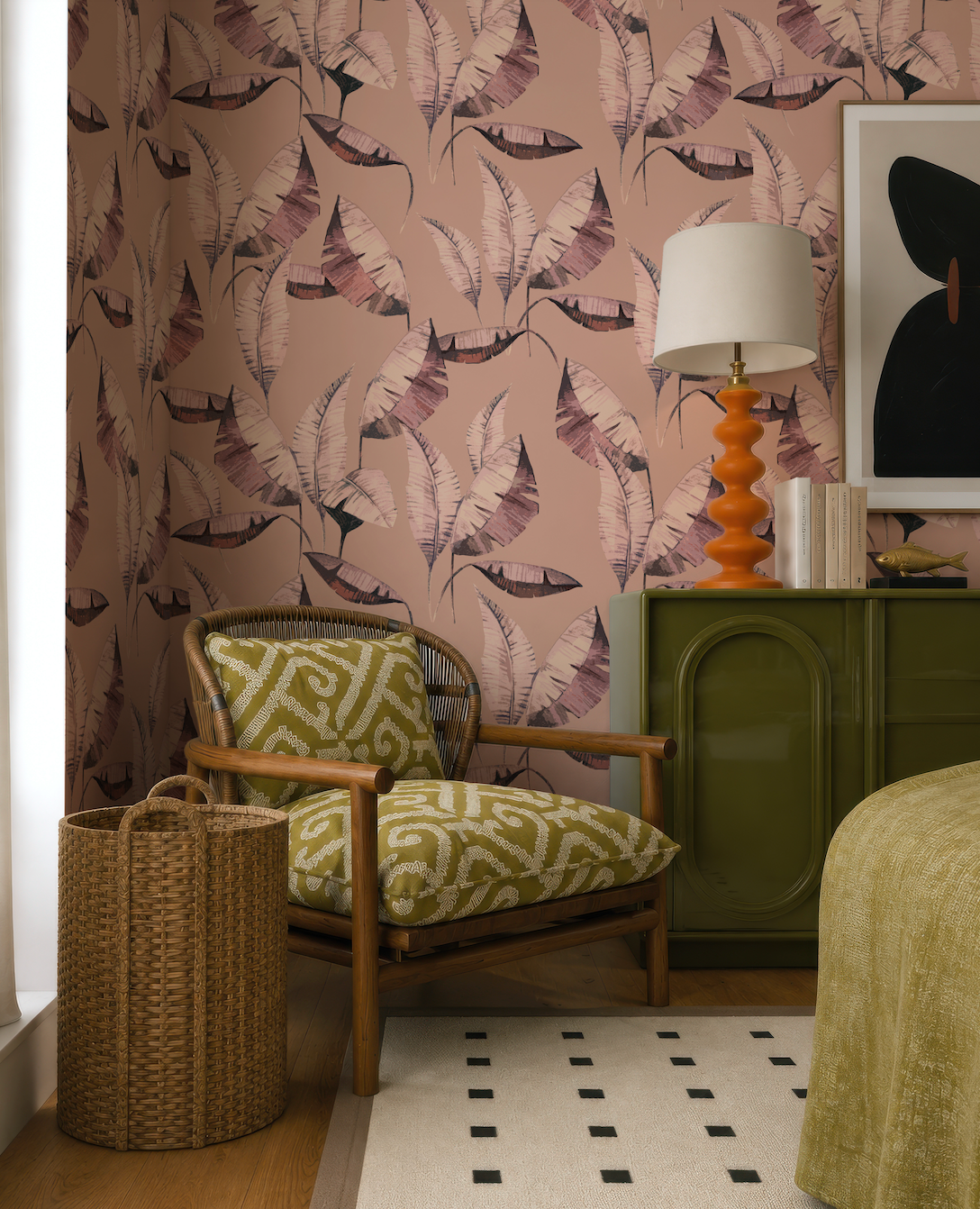 a cozy living room with a green armchair, a woven basket, and a patterned rug. The walls are adorned with a pink and purple leaf wallpaper, and there is a lamp on a green cabinet.