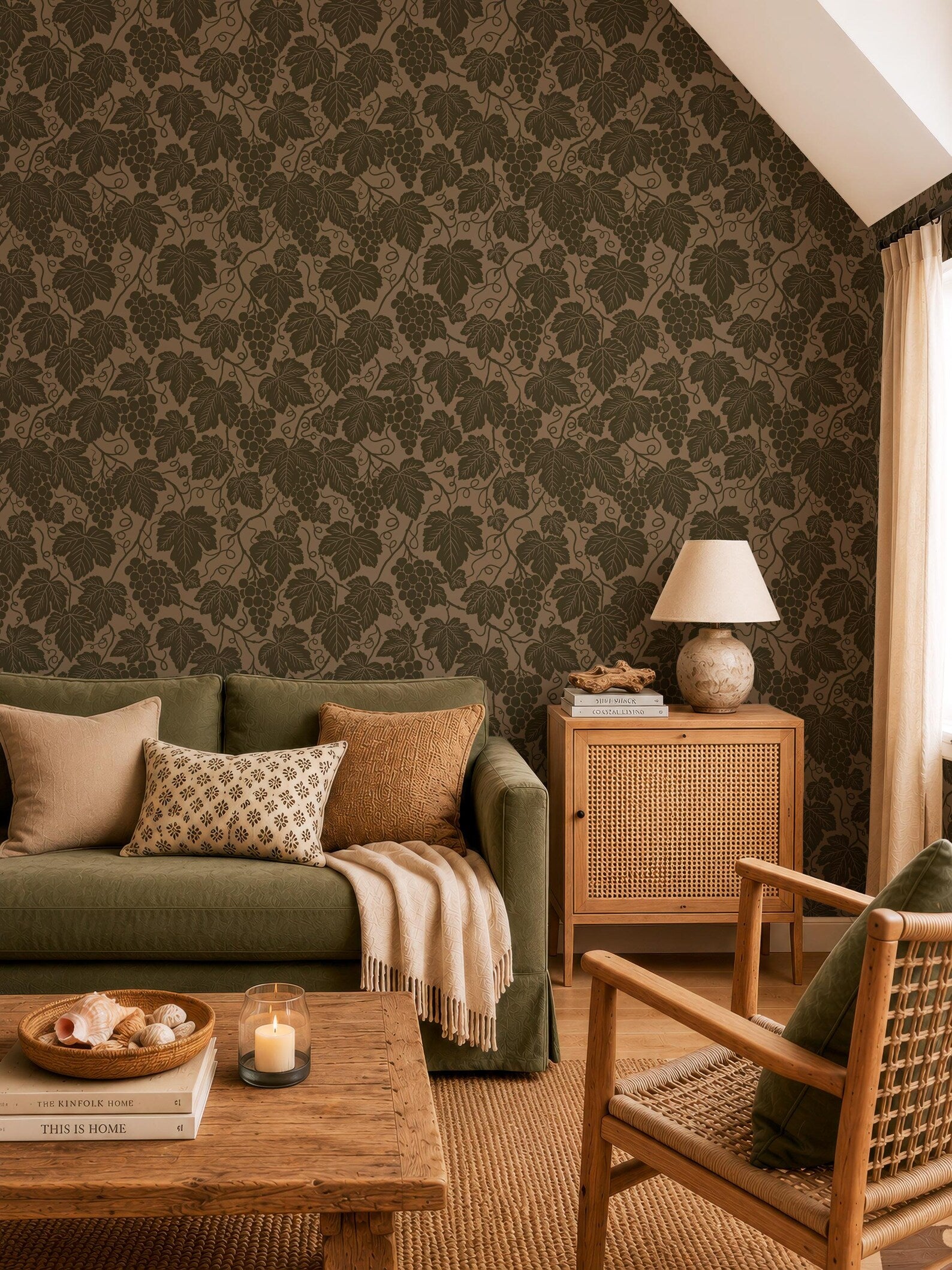 a cozy living room with a green sofa, a wooden coffee table, and a woven chair. The walls are covered in a patterned wallpaper with a repeating leaf design. The room has a warm and inviting atmosphere, with a lamp, books, and a bowl of fruit on the coffee table.
