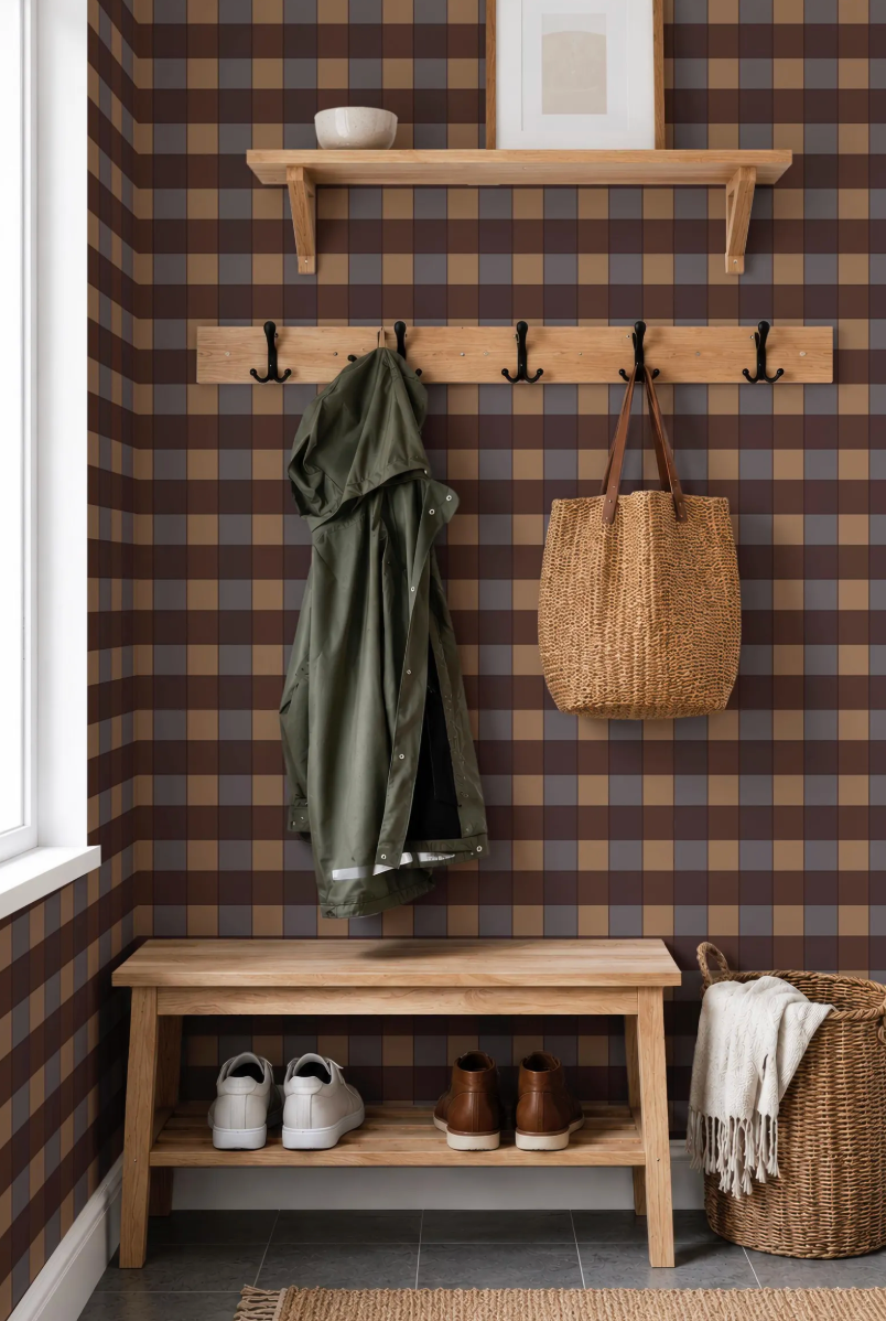 a cozy entryway with a wooden bench, a coat rack, and a basket. The wall behind the bench has a checkered pattern, and there is a picture hanging above the coat rack. The entryway also has a window and a shelf for storage.